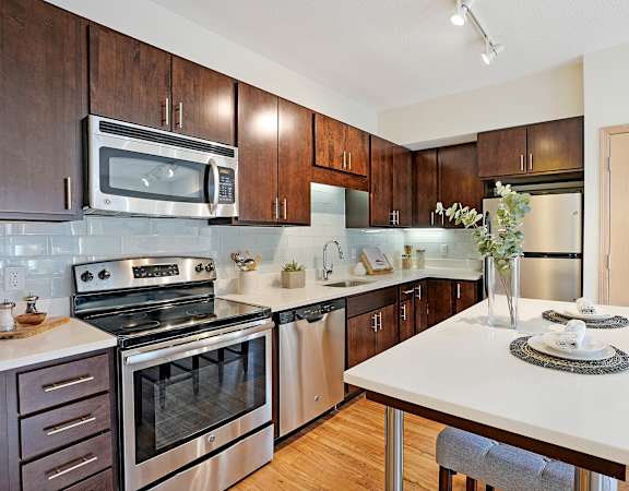 A kitchen with a white counter top and stainless steel appliances.