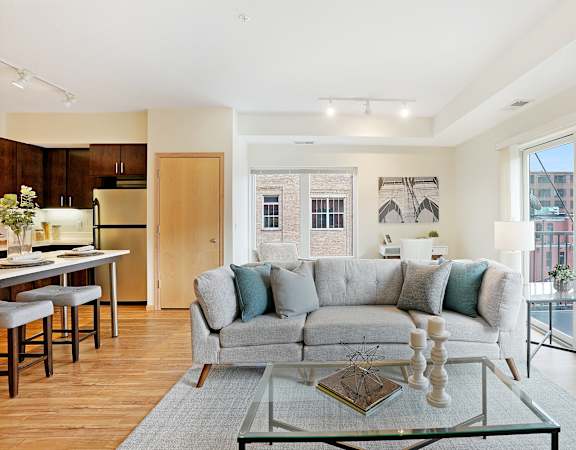 A modern living room with a grey couch and a glass coffee table.