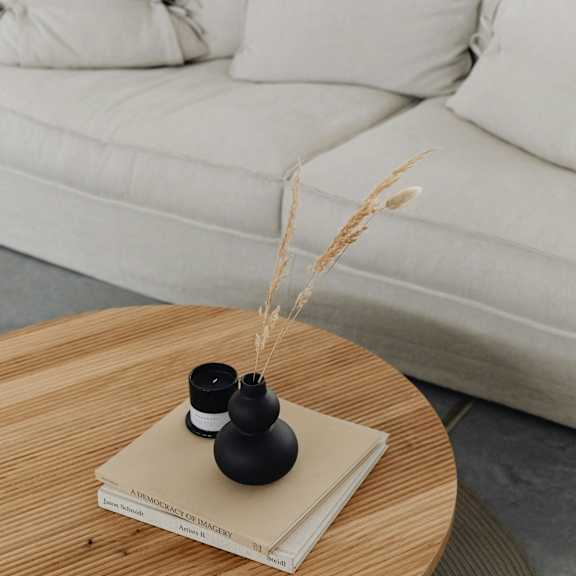 A wooden table with a book and two black vases on top of it.