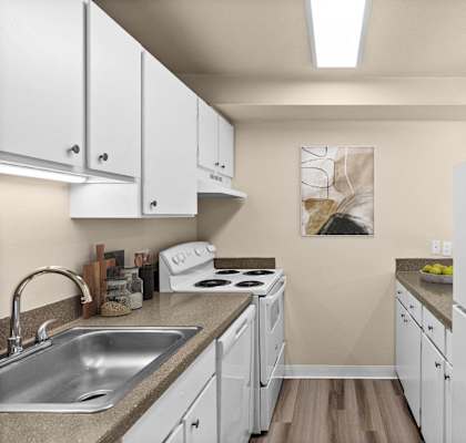 A kitchen with white cabinets and a white fridge.