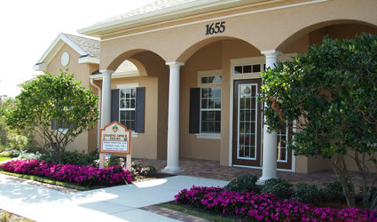 a building with a sign and flowers in front of it