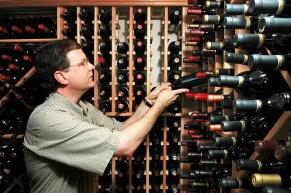 A man is selecting a bottle of wine from a wine rack.
