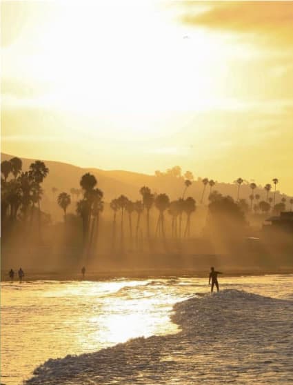 a person walking on the beach at sunset