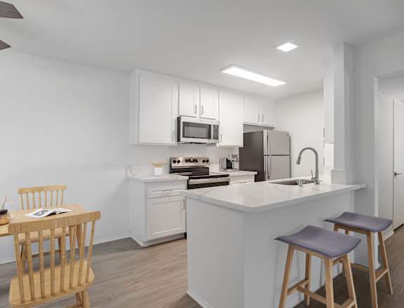 A modern kitchen with a white island and wooden stools.