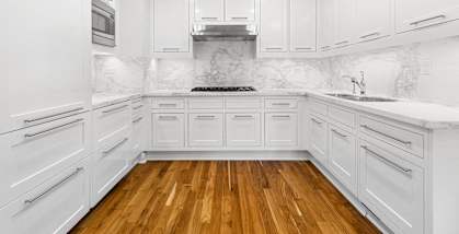 a white kitchen with white cabinets and a wood floor at HIGHGROVE, Stamford, Connecticut