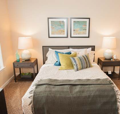 a bedroom with a bed and two nightstands and two paintings on the wall