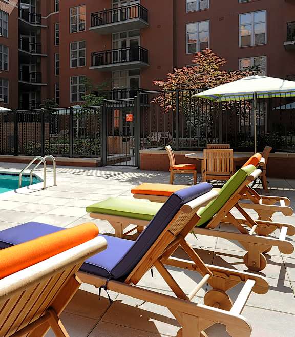 A pool surrounded by chairs and umbrellas.