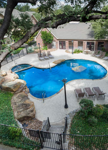 an aerial view of a swimming pool with a lazy river and patio furniture