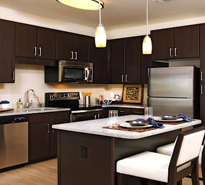 a kitchen with stainless steel appliances and a island with chairs