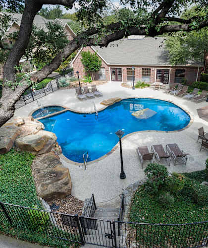 an aerial view of a swimming pool with a lazy river and patio furniture