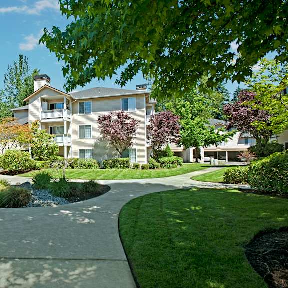 The stunning pathways surrounded by grass and trees leading to the apartment building at Windsong Apartment Homes.