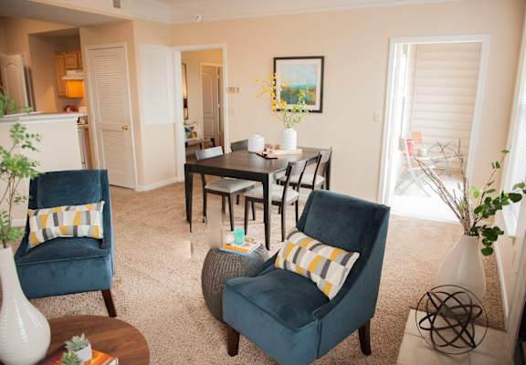 a living room with blue chairs and a dining room table