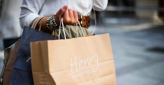 a woman holding a paper bag with her shopping bags