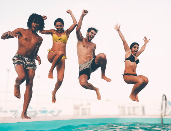a group of people jumping into a swimming pool