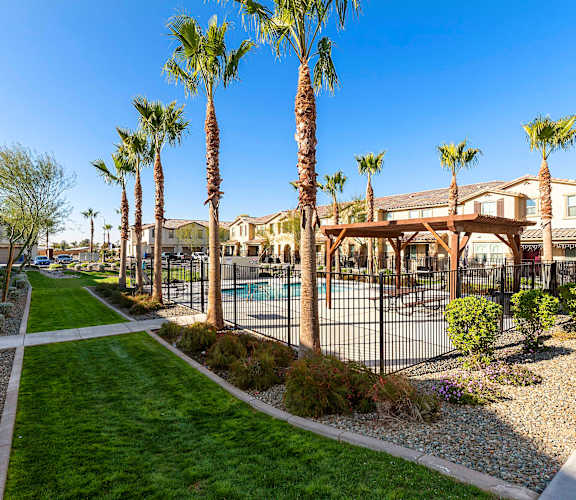 A sunny day at a residential area with palm trees and a pool. at Casa Sole Vita Townhomes, Arizona