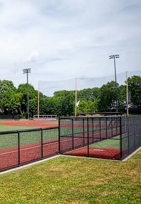 A track and field with a red track and a black fence.
