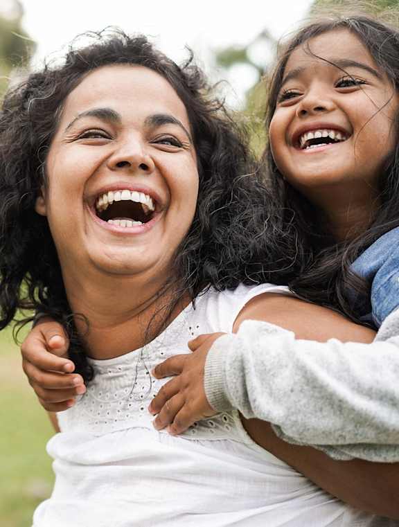 A woman and a young girl are laughing together in a park.at Union at 16th, Indiana