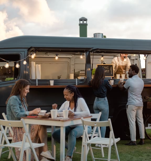 people eating at a table in front of a food truck at The Crest at South Point, McDonough, GA