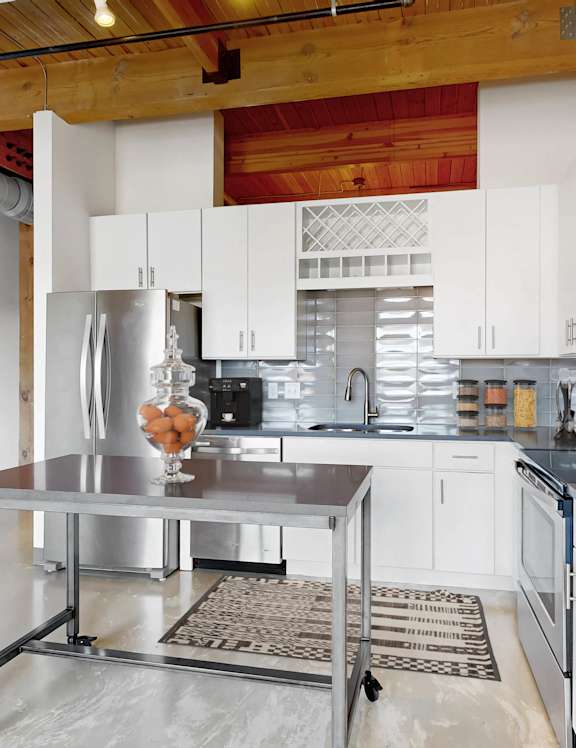A kitchen with white cabinets and a wooden ceiling.