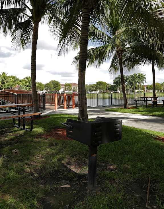 A park with a bench, lamp post and a fence.
