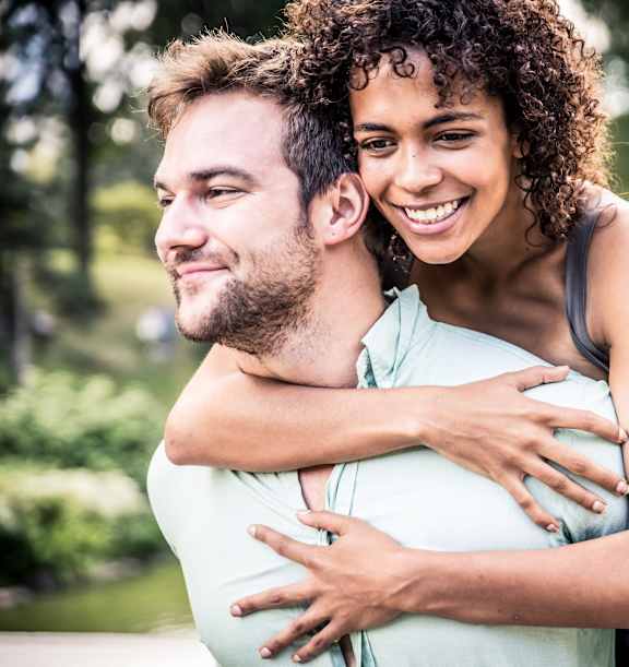 A man and a woman are hugging each other in a park.