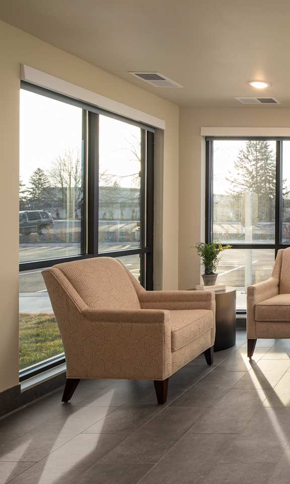 A living room with a couch, chairs, and a table with a vase of flowers on it.