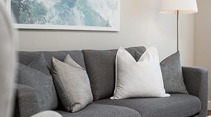 a gray couch with white pillows in a living room
