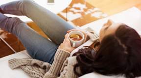 Woman relaxes on couch with coffee in the morning.