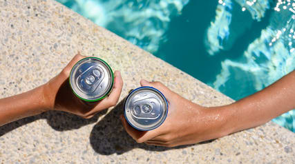 a person holding a beer next to a swimming pool