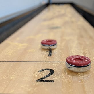 a game of shuffleboard on a wooden table with two numbers and two red buttons at Upscale Living at the Grand off 45th, Fargo, ND, 58104