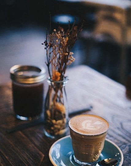 a cup of coffee and a vase of flowers on a table