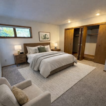 A room with a wooden floor and a kitchenette in the background.
