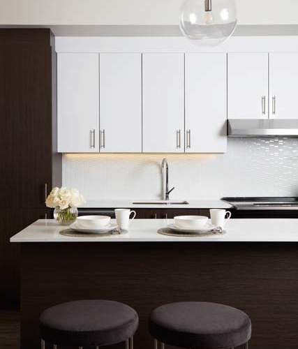 A kitchen with white cabinets and a dark brown counter.