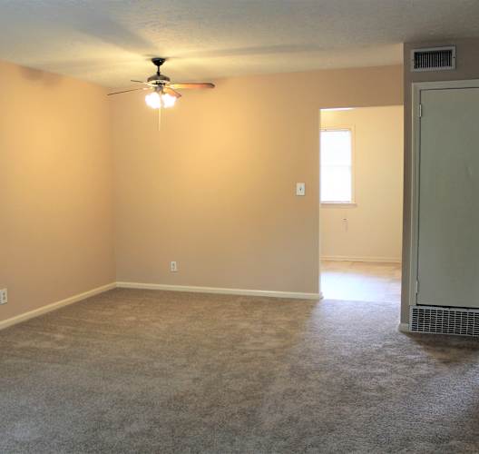 an empty living room with a ceiling fan and a door