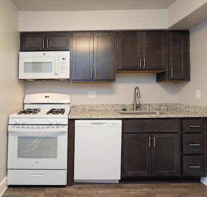 A kitchen with a white microwave above a white dishwasher and a white stove.at McDonogh Village Apartments & Townhomes, Randallstown, MD, 21133