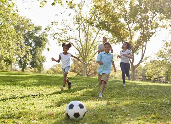 A group of people playing soccer in a park.