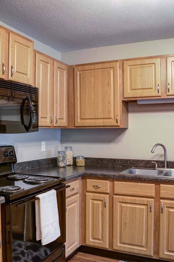 a kitchen with wooden cabinets and stainless steel appliances at Cityscape, St Louis Park, MN, 55416