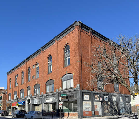A red brick building with a tree in front of it.