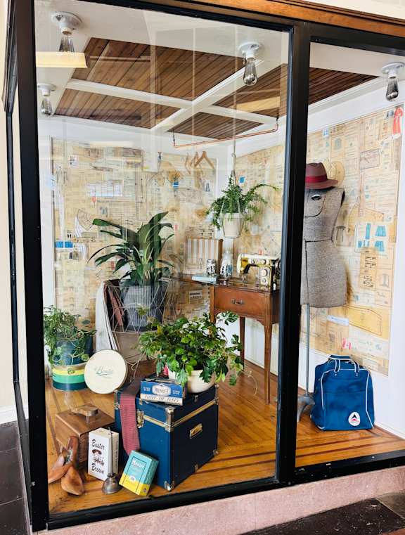 A room with a wooden floor and a wall covered in drawings and maps.