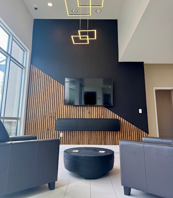 A modern living room with a black ottoman and grey couches.