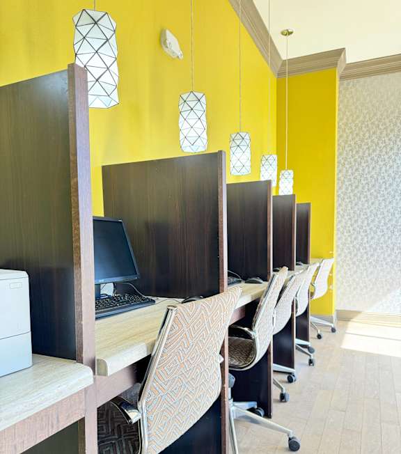 A row of chairs with a patterned cushion are in front of a yellow wall.