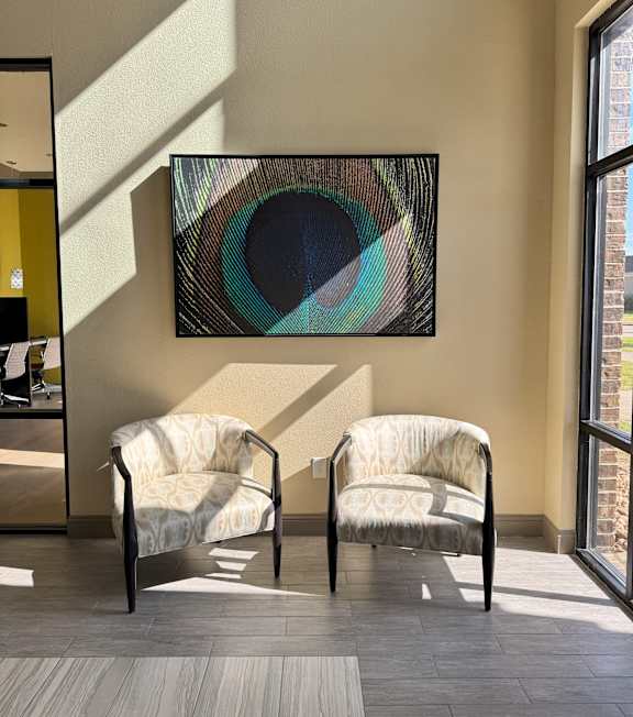 Two chairs are placed in front of a painting.