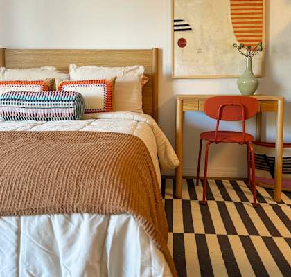 A bed with a brown blanket and a red chair in front of a painting at The Teale Siesta Lago in Kissimmee, FL, 34746