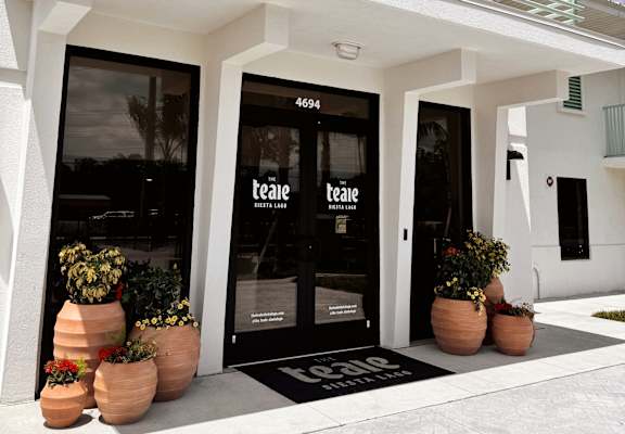 The front of a white building with a black door and windows.