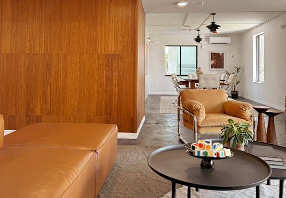 A living room with a brown leather couch and a wooden wall.