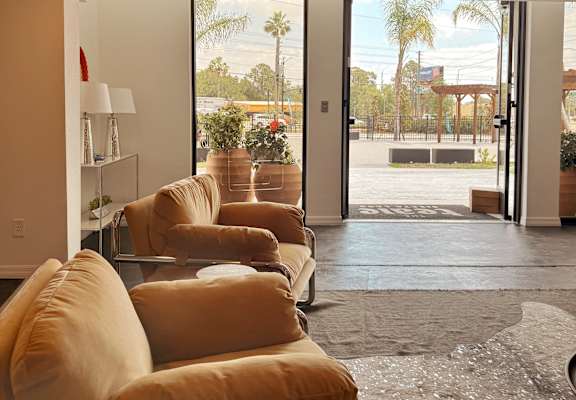 A living room with a row of couches and a view of the outdoors through the sliding glass doors.