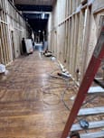 A long hallway with wooden floors and walls, and a few objects on the floor.