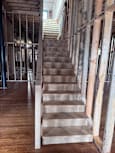 A wooden staircase with a metal railing is under construction.