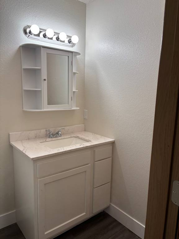 Remodeled bathroom vanity with mirror and white finishes at Muirfield Apartments.