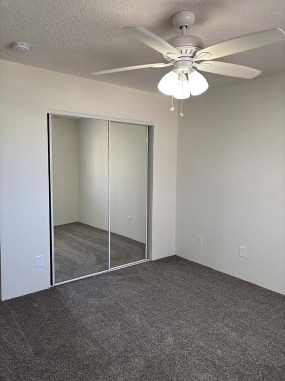 A bedroom with a ceiling fan and a closet sliding mirror door at Muirfield Apartments.